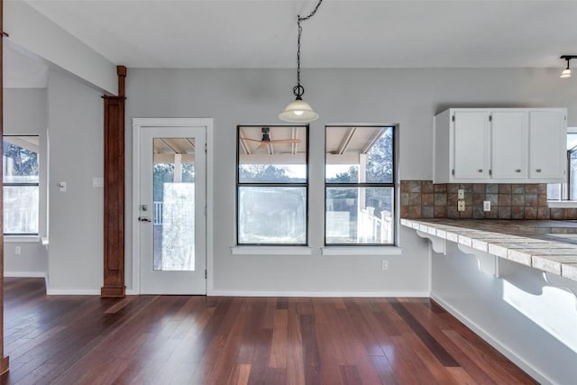 kitchen with tasteful backsplash, dark wood finished floors, white cabinetry, and pendant lighting