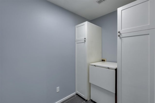 clothes washing area featuring visible vents, dark tile patterned floors, and baseboards