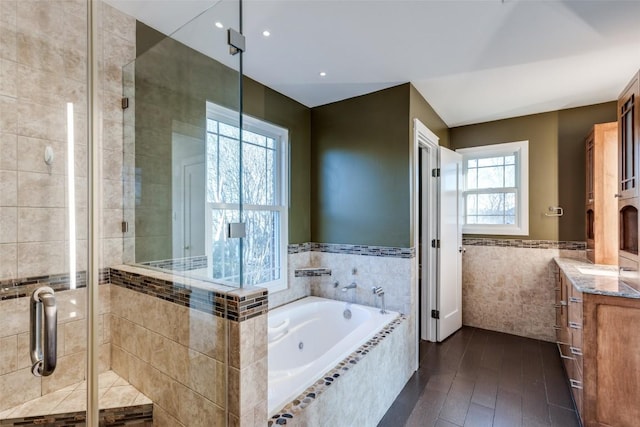 bathroom with a garden tub, vanity, tile walls, wainscoting, and a stall shower