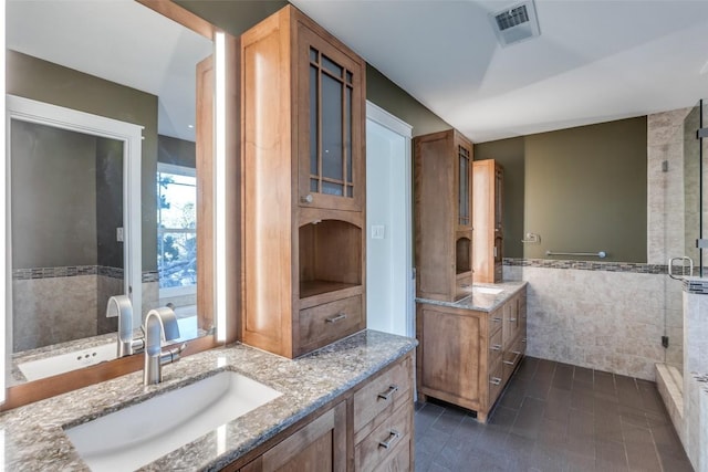 full bath featuring two vanities, a sink, visible vents, and tile walls