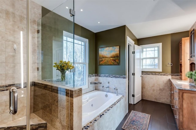 full bath featuring a stall shower, wood finished floors, tile walls, a bath, and vanity