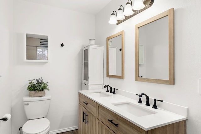 full bathroom with double vanity, toilet, and a sink