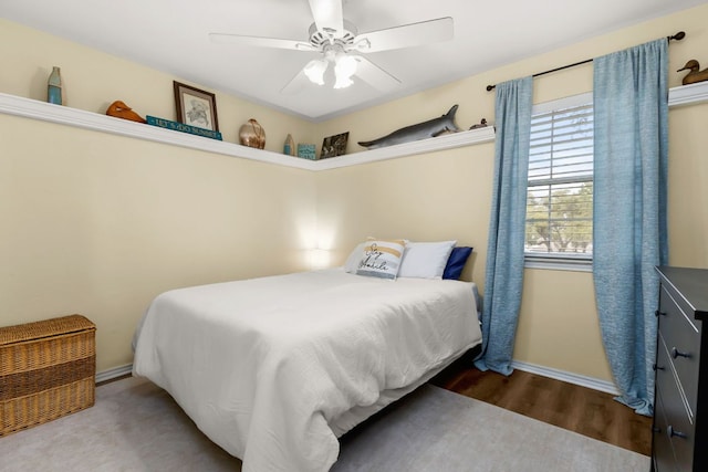 bedroom with wood finished floors, a ceiling fan, and baseboards