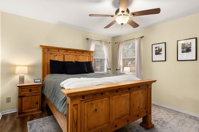 bedroom with a ceiling fan, baseboards, and dark wood-type flooring