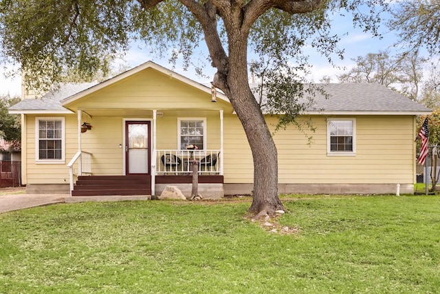 view of front facade featuring roof with shingles, a porch, and a front yard