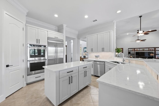 kitchen with light stone counters, visible vents, appliances with stainless steel finishes, white cabinets, and a sink