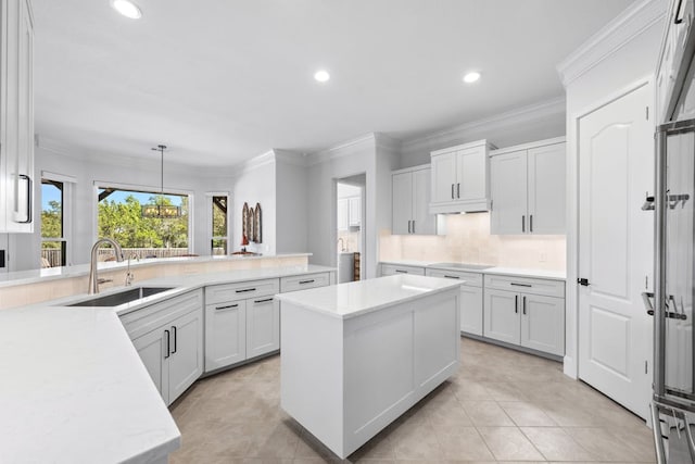 kitchen featuring pendant lighting, white cabinetry, a kitchen island, a sink, and stovetop