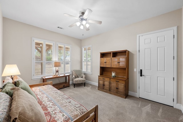 bedroom featuring a ceiling fan, visible vents, light carpet, and baseboards