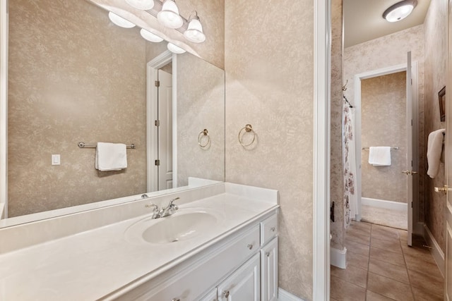 full bath with wallpapered walls, vanity, baseboards, and tile patterned floors