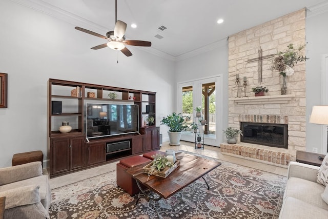 living room with light tile patterned floors, a fireplace, ornamental molding, and a ceiling fan