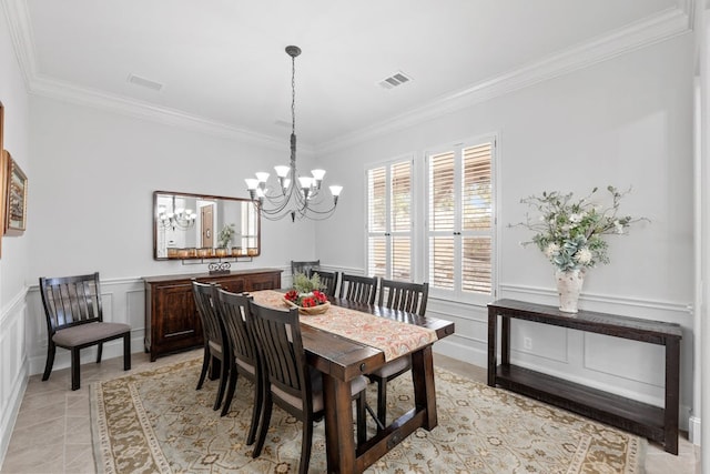 dining room with visible vents, a decorative wall, crown molding, and wainscoting