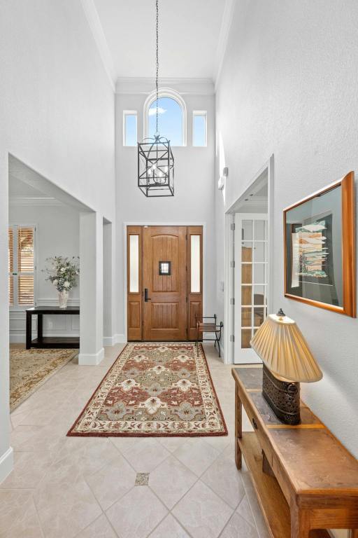 foyer entrance with a chandelier, ornamental molding, and plenty of natural light