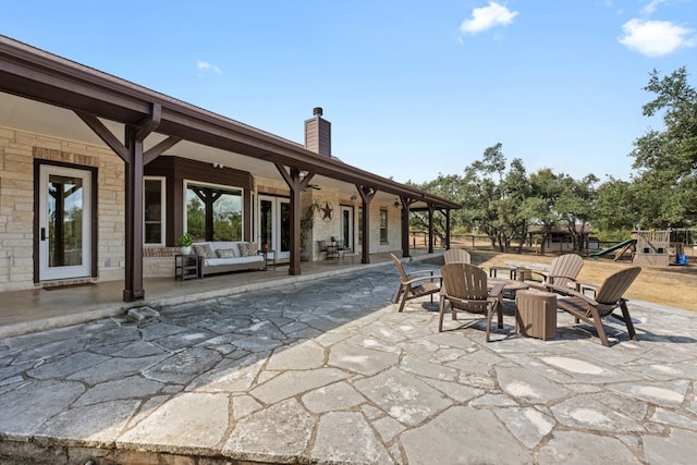 view of patio / terrace featuring a playground and an outdoor living space with a fire pit