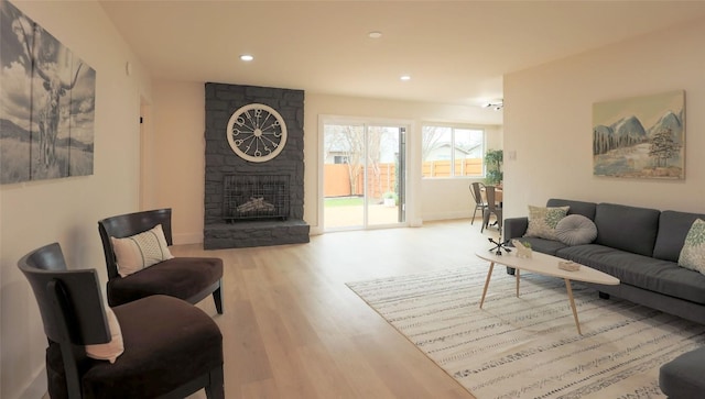 living area featuring light wood-style floors, a fireplace, baseboards, and recessed lighting