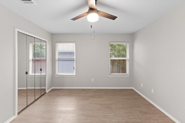 unfurnished bedroom with a closet, visible vents, ceiling fan, light wood-type flooring, and baseboards