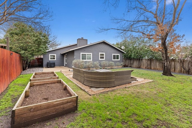 rear view of house with a lawn, a vegetable garden, a chimney, and a fenced backyard