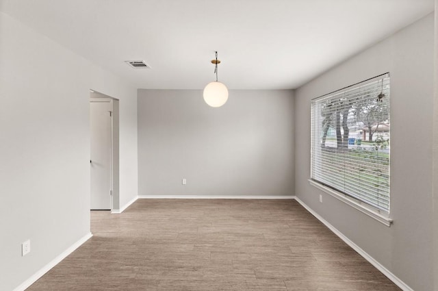 unfurnished room with baseboards, wood finished floors, and visible vents