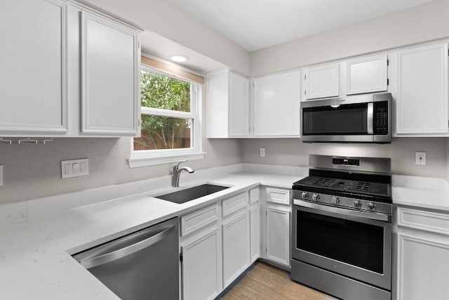 kitchen featuring stainless steel appliances, a sink, light countertops, and white cabinets