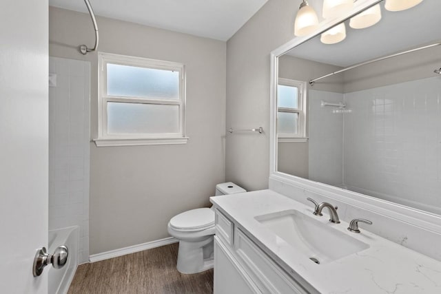 bathroom with bathing tub / shower combination, toilet, baseboards, wood finished floors, and vanity
