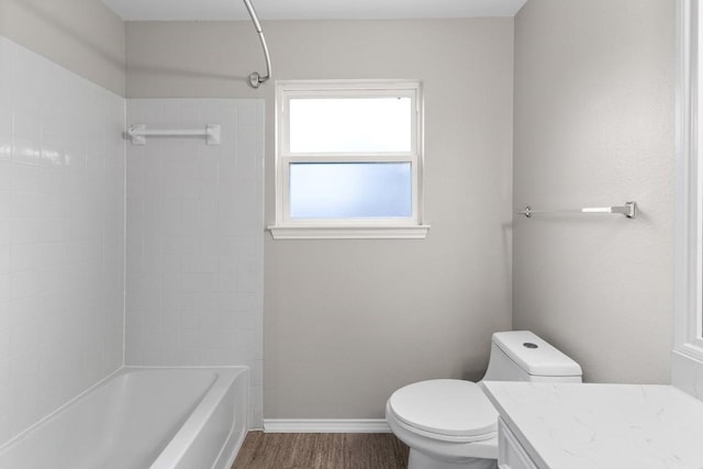 bathroom with toilet, washtub / shower combination, vanity, wood finished floors, and baseboards