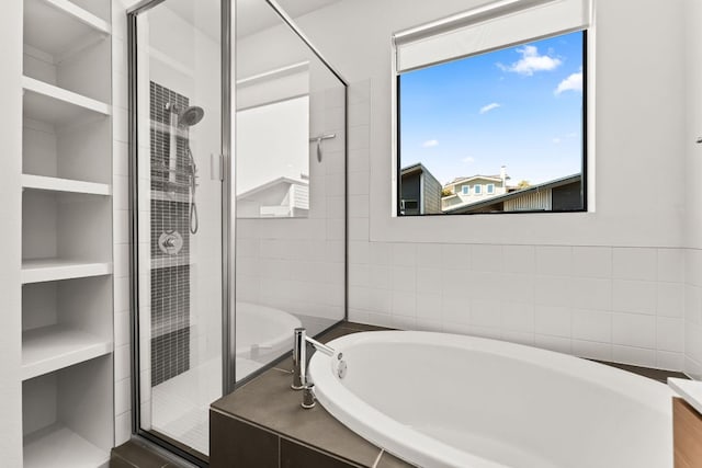 bathroom with built in shelves, a stall shower, and a bath