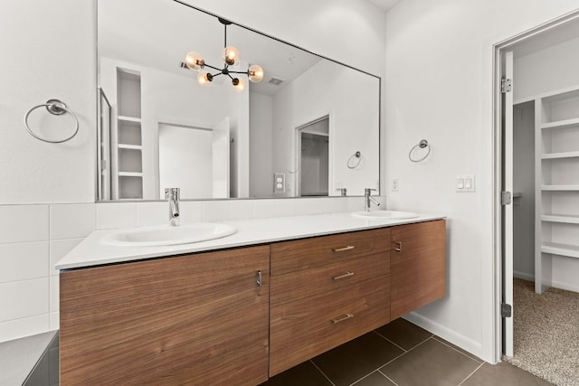 full bath featuring a chandelier, double vanity, tile patterned flooring, and a sink