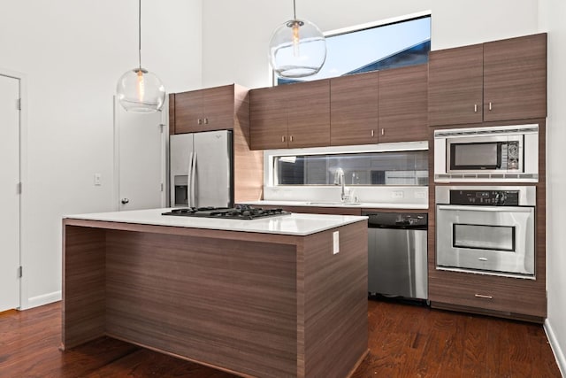 kitchen with a sink, stainless steel appliances, hanging light fixtures, and light countertops