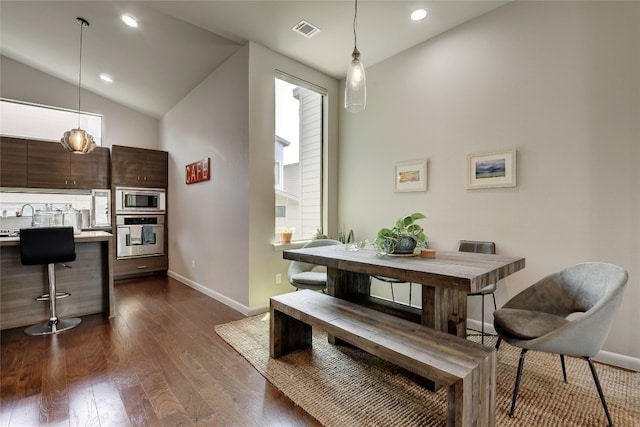 dining space with dark wood finished floors, visible vents, vaulted ceiling, and baseboards