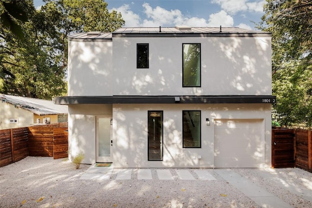 back of house featuring a standing seam roof, stucco siding, fence, and metal roof