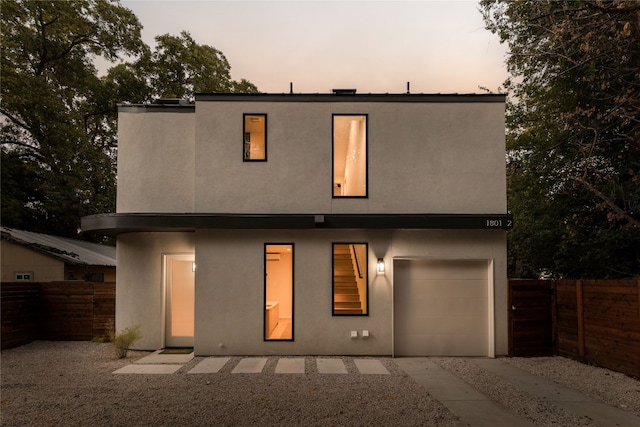 view of front of house featuring fence, a garage, and stucco siding