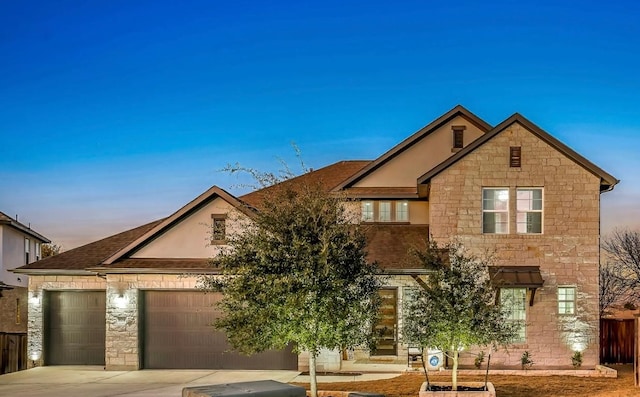 view of front facade with an attached garage, stone siding, and driveway