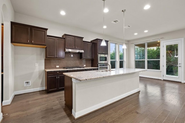 kitchen featuring pendant lighting, visible vents, appliances with stainless steel finishes, an island with sink, and under cabinet range hood