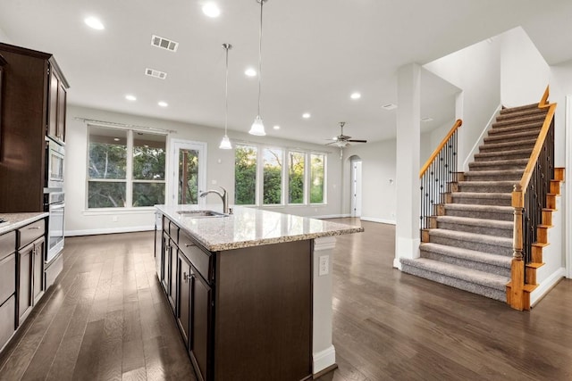 kitchen with stainless steel appliances, visible vents, hanging light fixtures, a sink, and an island with sink