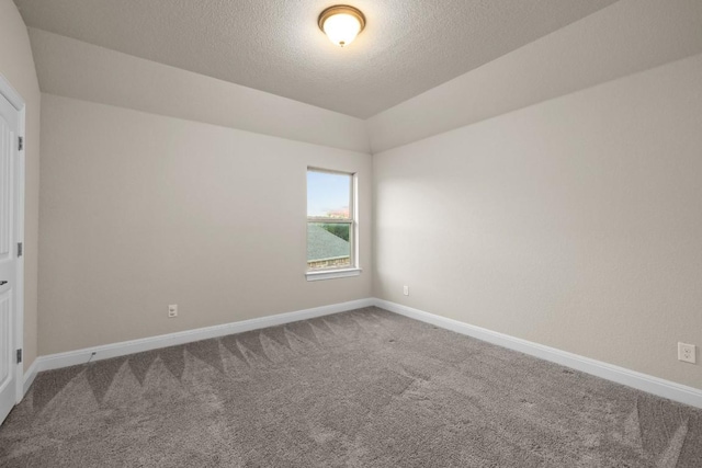 carpeted spare room featuring a textured ceiling and baseboards