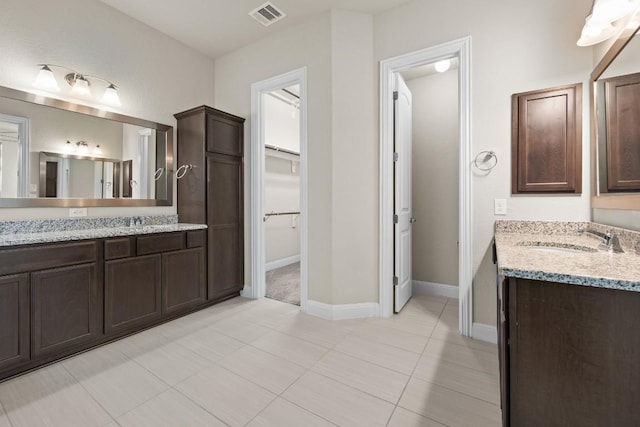 full bathroom featuring a spacious closet, two vanities, a sink, and visible vents