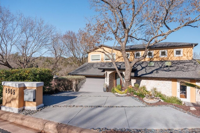 view of front of home featuring stone siding and concrete driveway