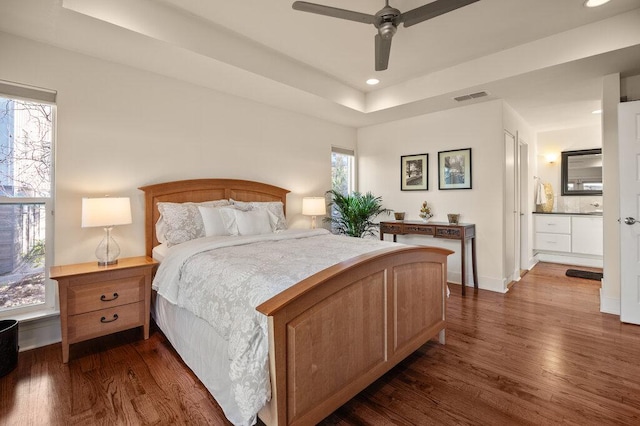 bedroom with dark wood-style floors, recessed lighting, a raised ceiling, visible vents, and baseboards