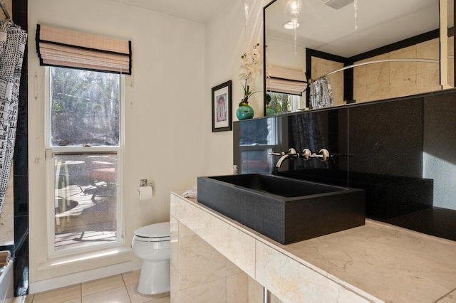 bathroom with toilet, a sink, a wealth of natural light, and tile patterned floors