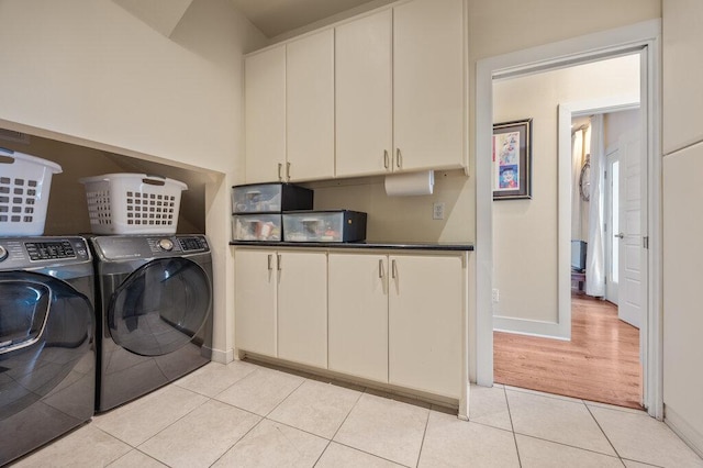 washroom with light tile patterned floors, separate washer and dryer, cabinet space, and baseboards