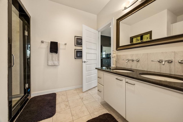 full bathroom featuring double vanity, a shower stall, a sink, and tile patterned floors