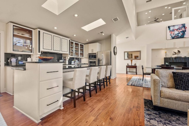 kitchen featuring dark countertops, stainless steel appliances, glass insert cabinets, and white cabinets