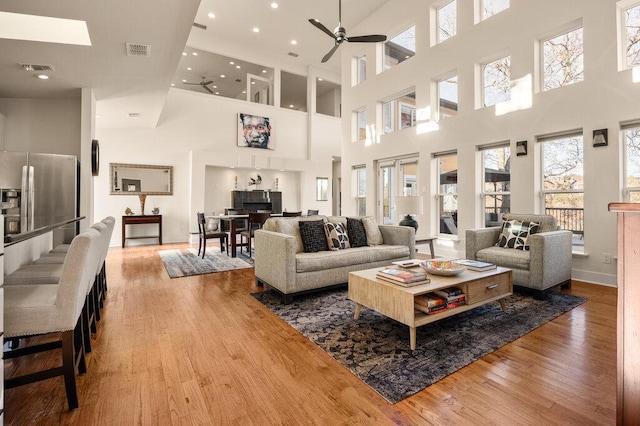 living area with a ceiling fan, visible vents, and light wood-style flooring