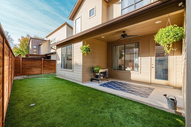 rear view of house with a patio area, a fenced backyard, a lawn, and a ceiling fan