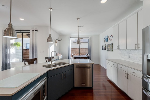 kitchen featuring stainless steel appliances, light countertops, white cabinets, and pendant lighting