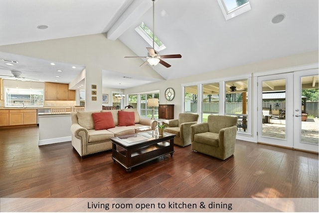 living room featuring a skylight, beam ceiling, dark wood-type flooring, and ceiling fan with notable chandelier