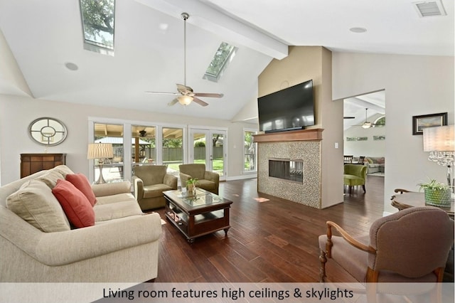 living room with a skylight, dark wood-style floors, visible vents, and a ceiling fan