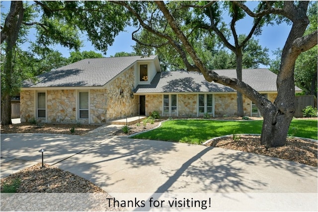 view of front of property featuring a shingled roof, a front yard, and fence