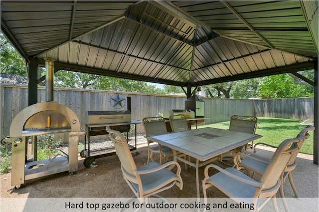 view of patio with outdoor dining space, fence, and a gazebo