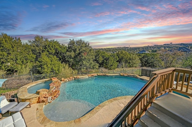 pool at dusk featuring a fenced backyard and a fenced in pool