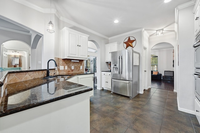 kitchen with arched walkways, white cabinets, dark stone countertops, a sink, and stainless steel appliances